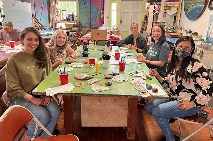 Community members, including Teresa Lavagnino, gathered around a table painting rocks.