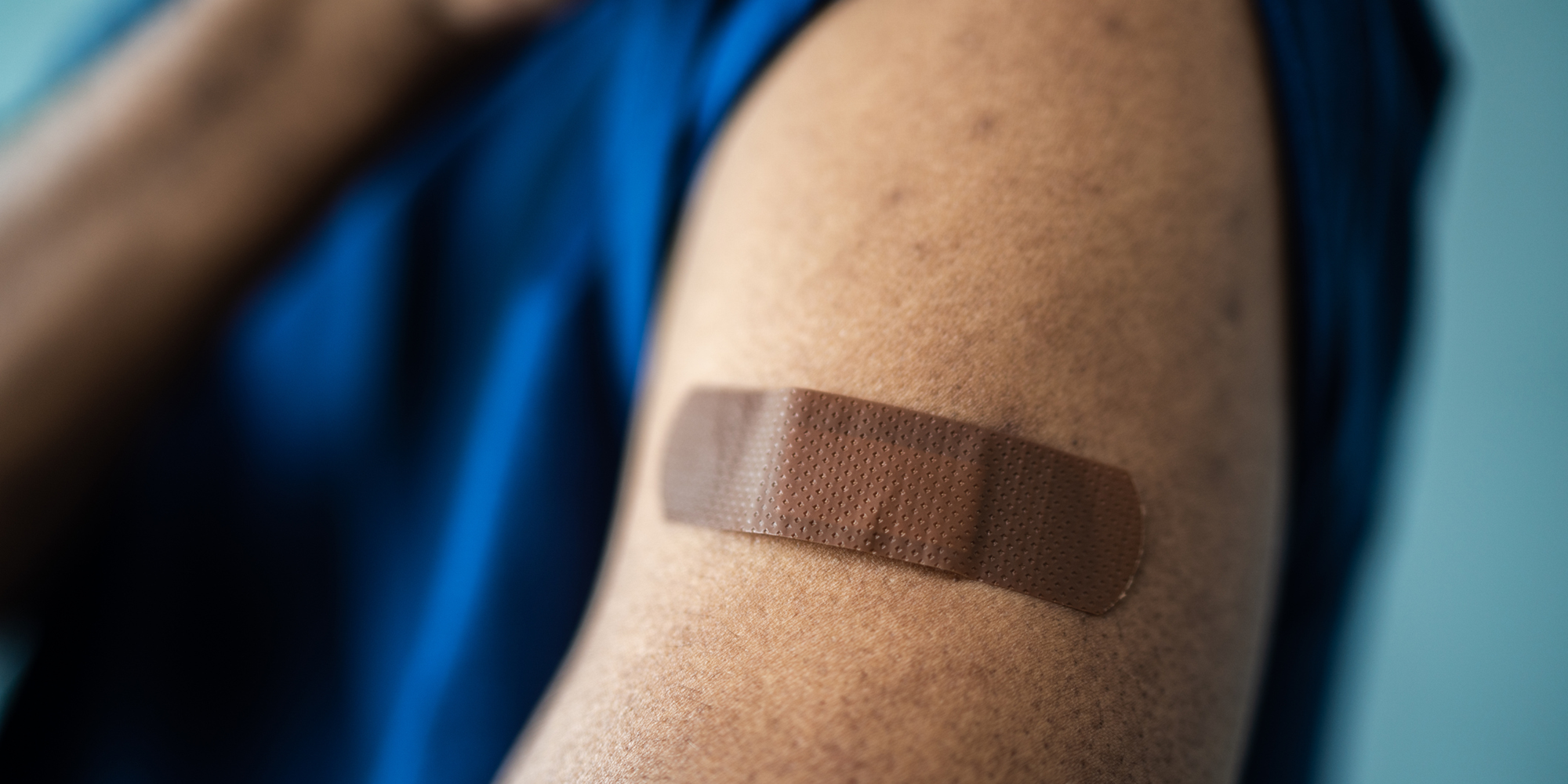 Closeup image of a person with a band aid on their arm.